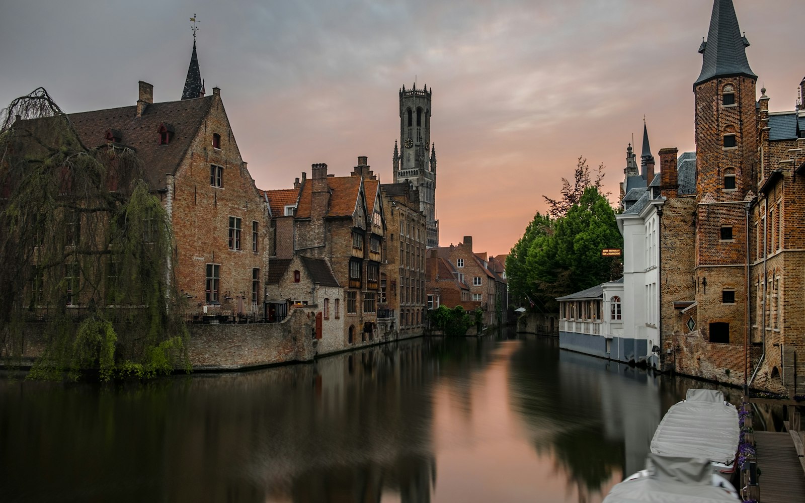 Bruges' stepped-gable houses reflected in a still canal beneath a medieval belfry