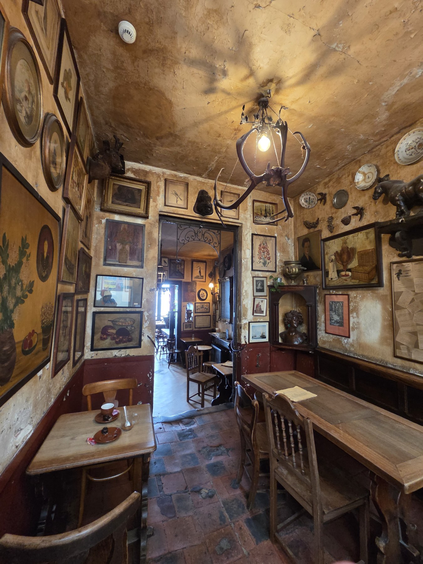 The cluttered, art-covered interior of La Fleur en Papier Doré in Brussels, walls crowded with framed pictures and curios