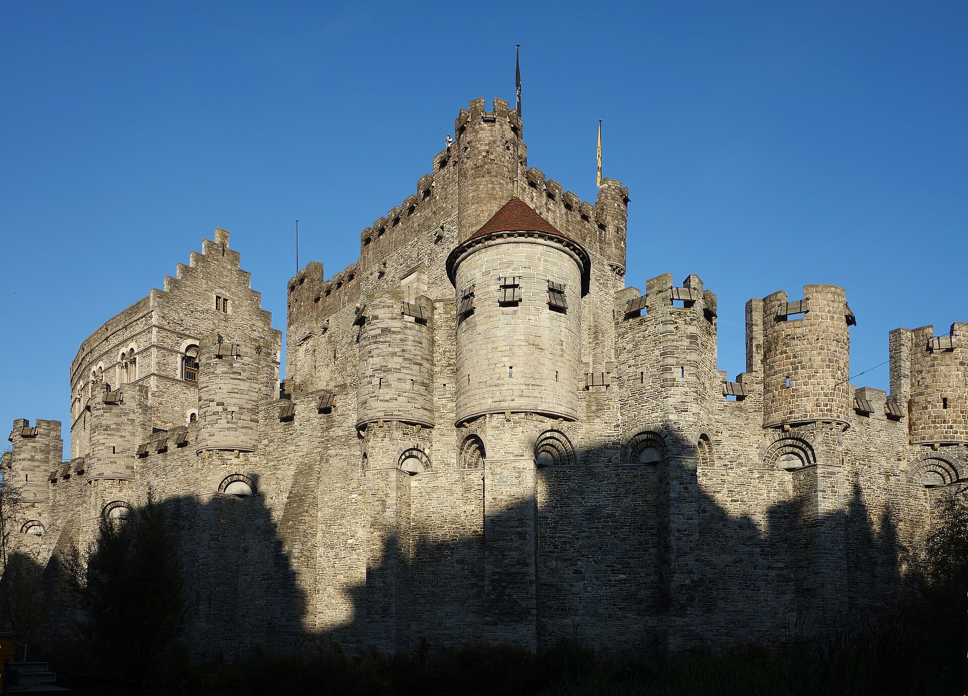 The battlemented stone walls and towers of Gravensteen castle rising against the sky in central Ghent