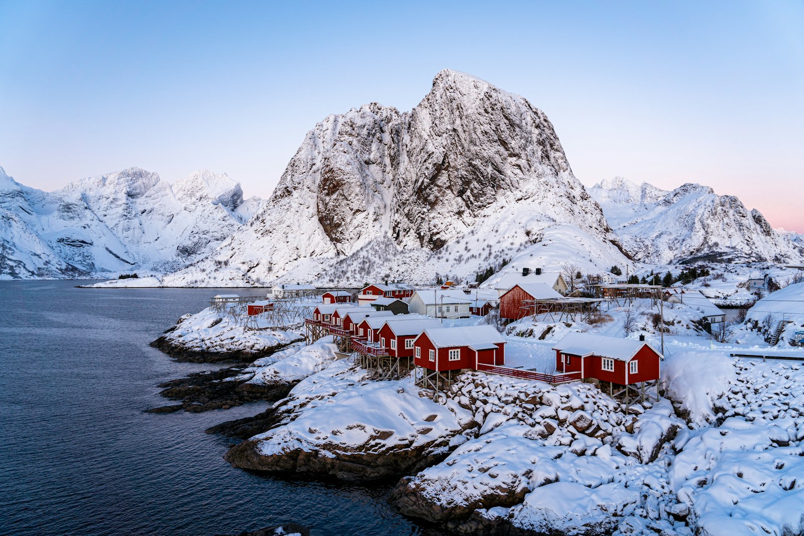 Red fishermen's cabins in Reine beneath sheer granite peaks above the Arctic water