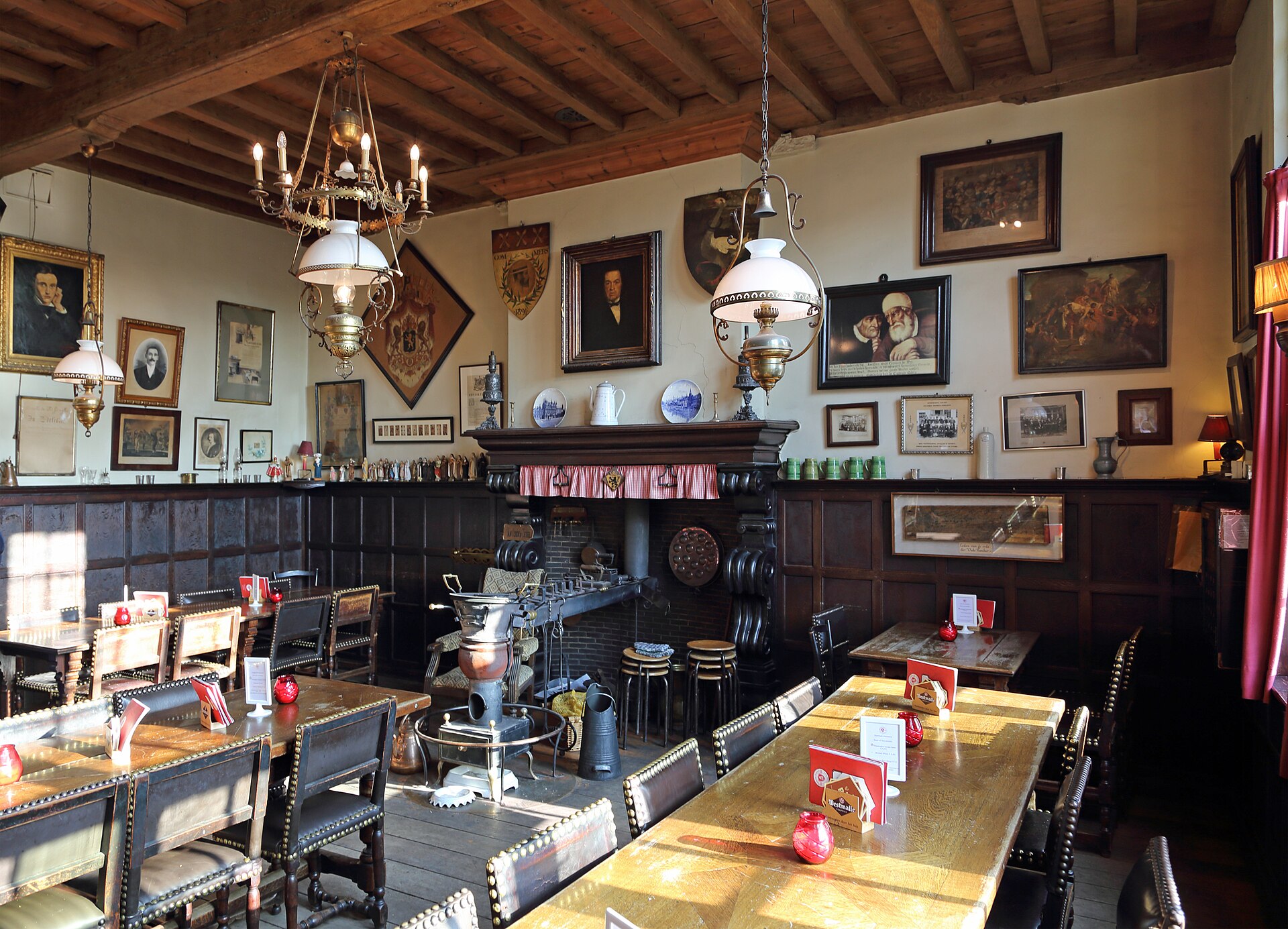 The candlelit, wood-panelled interior of Café Vlissinghe in Bruges, hung with old paintings beneath a beamed ceiling
