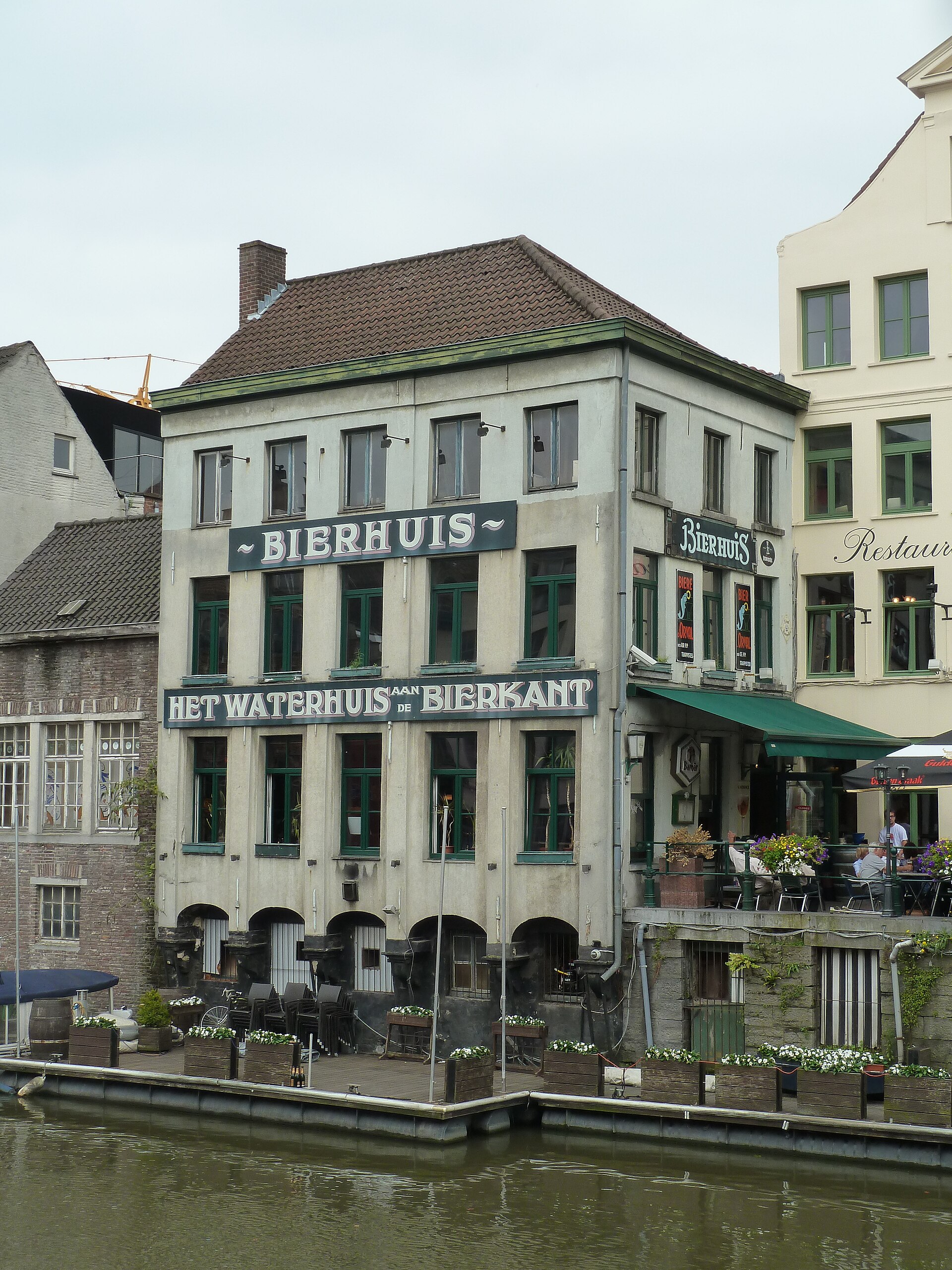 The painted canal-side façade of Het Waterhuis aan de Bierkant beer house in Ghent, reflected in the water